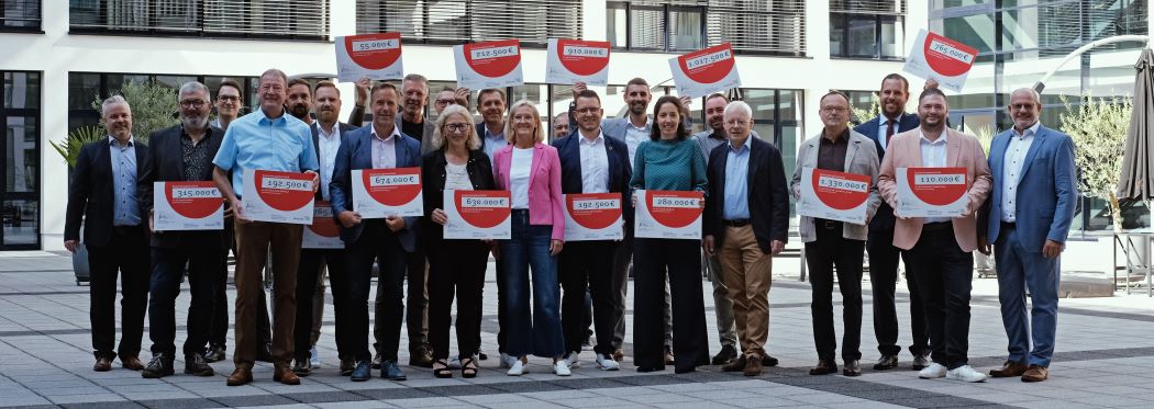Gruppenfoto der 14 Bürgermeisterinnen und Bürgermeister sowie der Vertreter des Landes und des eGo-Saar mit den Schecks über die jeweiligen Förderungen